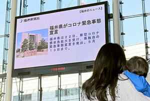 福井県独自の緊急事態宣言のニュースを伝える大型ビジョン＝４月２２日、福井県福井市のハピテラス
