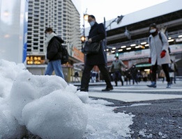 まとまった積雪から一夜明け、足元に気を付けながら通勤する人たち＝２０２２年１月７日午前、東京・ＪＲ新橋駅前